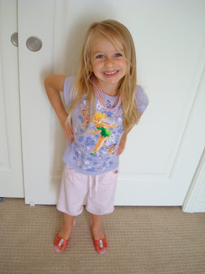 Young girl standing in front of door with hands on hips smiling