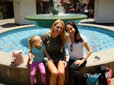 Two woman and young girl sitting in front of fountain