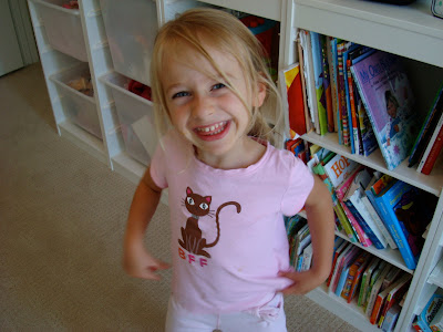 Young girl standing in front of book shelves smiling
