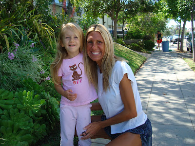 Woman and child on side walk next to plants embracing and smiling