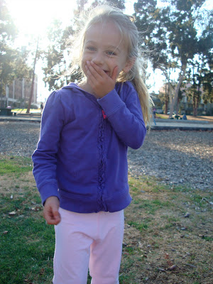 Young girl with hand over mouth standing at park