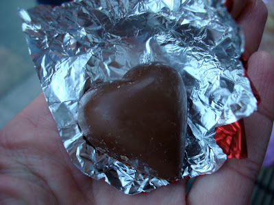 Hand holding unwrapped heart shaped chocolate