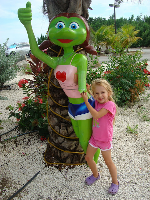 Young girl posing next to green frog like lady fixture