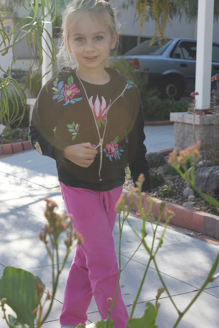 Young girl with flowered hoodie on sidewalk