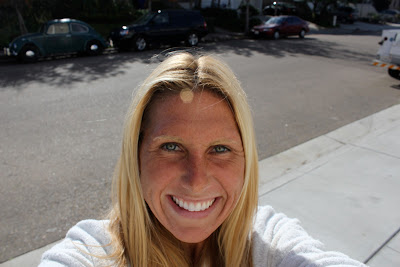 Woman taking photo of self smiling on sidewalk