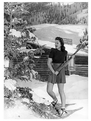 Ann Rutherford chopping down her Christmas tree in culottes and high heels