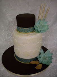 Extended base tier with sugar paste lace overlay with sugar magnolias and sugar bamboo sticks.