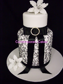 Extended base tier  cake with C scroll piping and white sugar lilies.