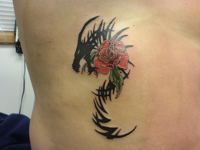 Black tribal dragon and red rose tattoo on the body.