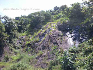 small rock mountain,green vegetation covered rock mountain seed aside the roadstrip to thenmala eco tourism point,dark rock face wet in winter spring