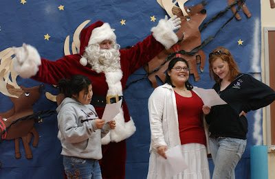 KODIAK, Alaska – Santa, portrayed by Coast Guard Commander Scott Williams, dances to the musical voices of three choir members from the Larson Bay school choir as they sing “Never do a Tango with an Eskimo”. Santa was brought to Larson Bay by a Coast Guard MH-60 Jayhawk helicopter crew from Air Station Kodiak as part of the annual Santa to the Villages program here. Santa to the Villages is sponsored by the Coast Guard Officer’s Spouses Association as a way to allow the children of remote villages around Kodiak Island to experience the joy of meeting Santa and receive a gift from him. During Santa’s visit to the school, each student was presented with a small gift and a candy cane. Hats and gloves were given to the younger students. The Coast Guard has been transporting Santa and the elves by boat and helicopter to the remote villages of Kodiak Island for more than thirty years. (Official Coast Guard photo by Petty Officer Richard W. Brahm)