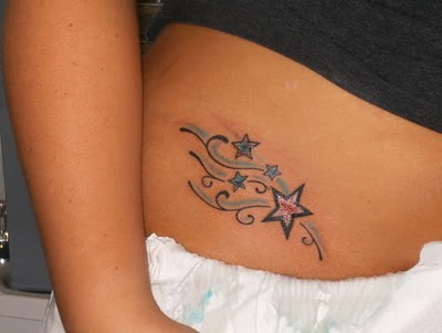 Un tatuaje donde el tribal se combina con estrellas de colores en la cintura