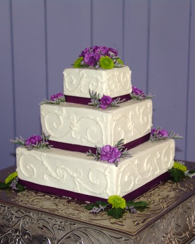 Four tier white textured wedding cake generously decorated with lovely 