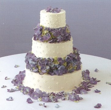 Three tier round white icing wedding cake with lots of vivid blue and purple