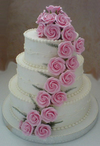 Classic three tier white wedding cake with light pink sugar roses cascading Classic three tier white wedding cake with light pink sugar roses cascading