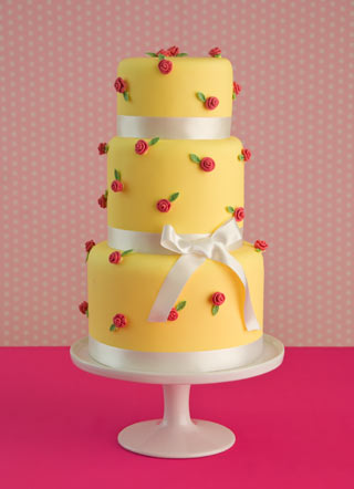 Pretty pastel yellow wedding cake with small red sugar roses over three Pretty pastel yellow wedding cake with small red sugar roses over three