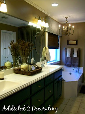 Master bathroom makeover--decorative mirrors added over plate glass mirror, accessories, chandelier over bathtub, valance, woven Roman shade