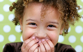 Photo of a child covering their mouth while laughing