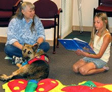 photo of Ginny and Addie being read to by a little girl at the library