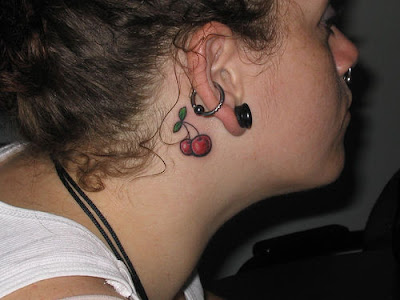 Small cherry tattoo behind the ear.