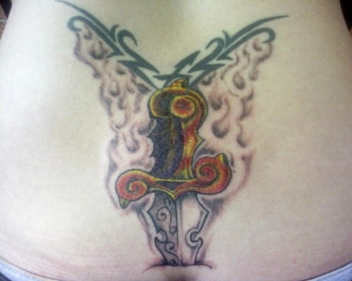 Pierced dagger tattoo on lower back.