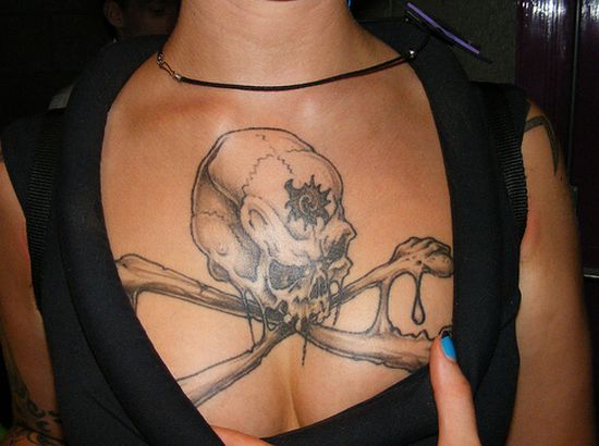 Large skull and crossbones chest tattoo on girl.