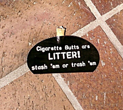 Picture of a brown sticker that reads Cigarette butts are litter stash'em or trash 'em in white.  A cigarette butt is protruding from the sticker. 