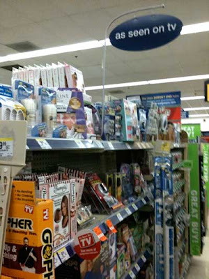 Store shelves crammed with products, sign above says As Seen on TV
