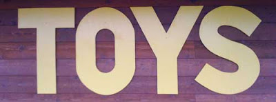 Yellow letters on side of building reading TOYS