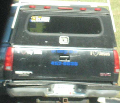 Tailgate of a black pickup truck with I love my wife and I love Jesus bumper stickers at either end