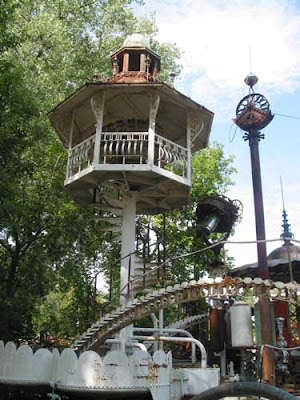 A metal gazebo atop a spiral staircase, connected to the sculpture