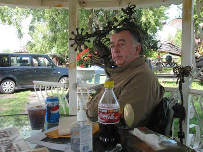 A man with graying hair, sitting at a table in a gazebo