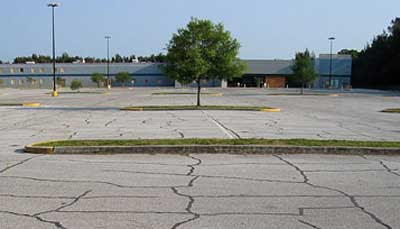Cracked asphalt sea with a Wall Mart store visible in the distance