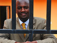 Journalist Andrew Mwenda photographed through prison bars