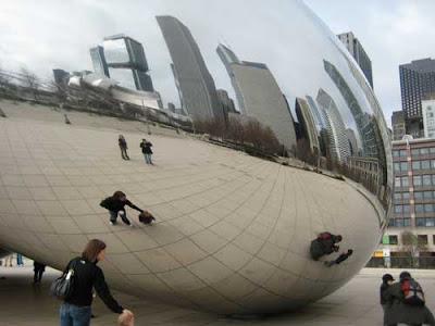 Highly reflective curved surface showing tall buildings and people
