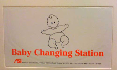 Beige changing table with red letters and a black line drawing of a baby with arms out, curly forelock of hair