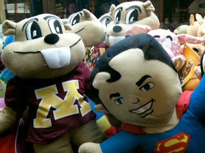 Square-featured Superman doll face pressed up against the glaass, surrounded by other dolls