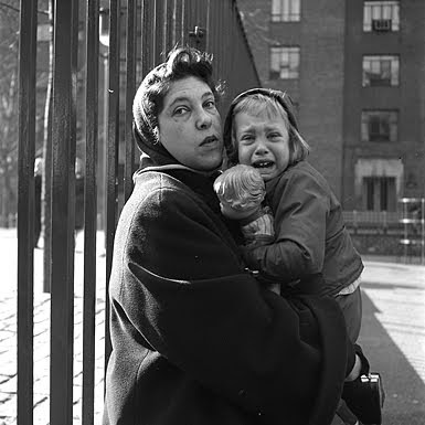 1950s photo of woman in scarf holding a crying preschooler