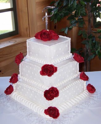 3 tier square cake with polka dots and accented with red silk roses at each