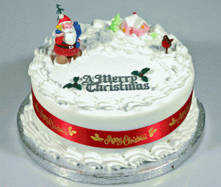 A Merry Christmas in green letters written on Cool christmas cake with red Santa Clause on it and penguins, red straped around the cake hot image