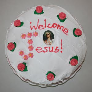 White cake with red frosting reading "welcome Jesus"