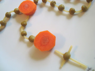 End of edible rosary with pasta, carrots, and peas