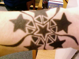 Lindo mosaico em preto de estrelas misturadas com motivos tribais tatuado no pulso, formando um bracelete