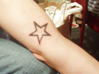 Tatuagem simples de estrela na lateral do braço, próxima ao cotovelo