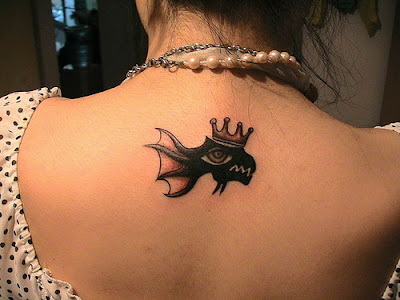 A cute goldfish tattoo on the back wearing a crown and with beard.