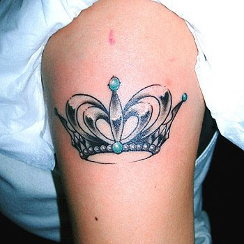 A crown tattoo on the arm with several sapphires on it.