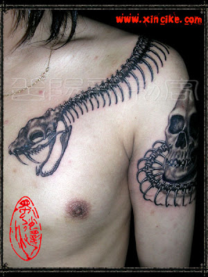 A combination of a skeleton snake and a human skull tattoo on the shoulder