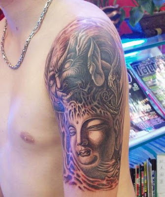 Buddha tattoo on the arm with a demon face over the head.