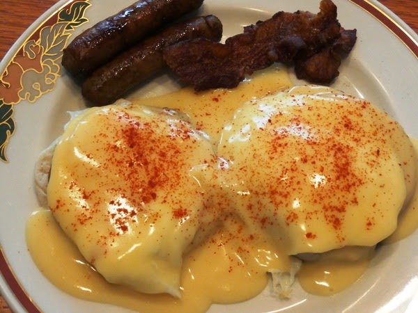 Eggs Benedict on a plate with sausage and baco