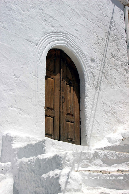 A white-painted staircase leading to a wooden door of a white cubic house.
